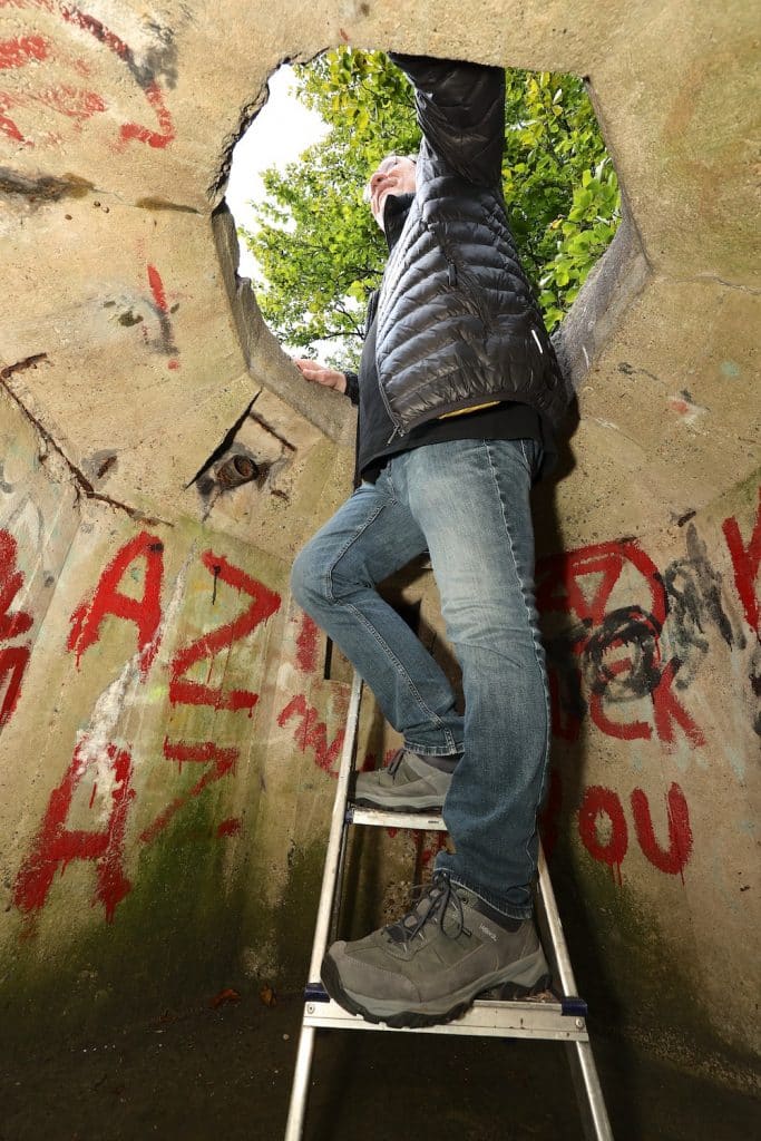 Bunker Alkmaardenhout, man kijkt door het gat bovenin de bunker naar buiten.