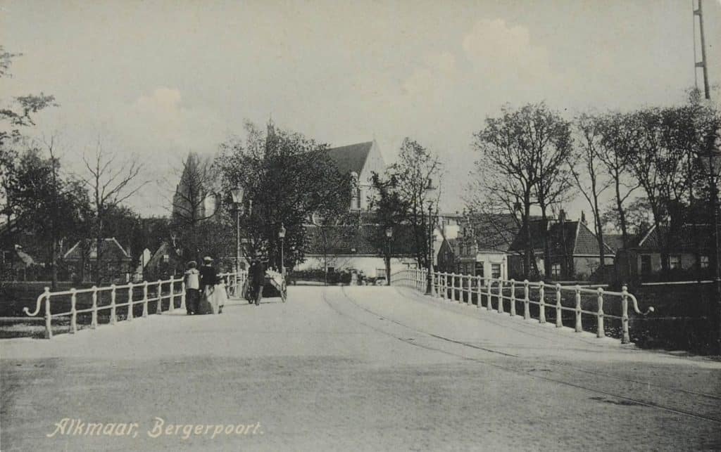 De Grote Sint Laurenskerk 1906 Prentbriefkaart Bergerbrug met voetgangers en een man met een kar. Op de voorgrond de Geesterweg. Op de achtergrond de Grote Sint Laurenskerk. Collectie Regionaal Archief Alkmaar-RAA012001103