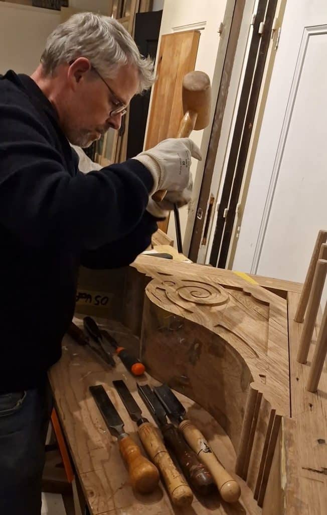 Jaap bewerkt een houten korbeel in zijn werkplaats aan de Laat