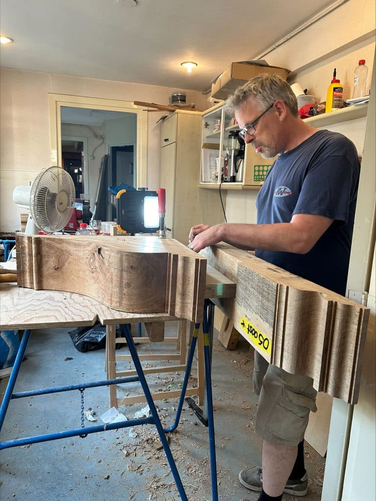 Jaap bewerkt een houten korbeel in zijn werkplaats aan de Laat