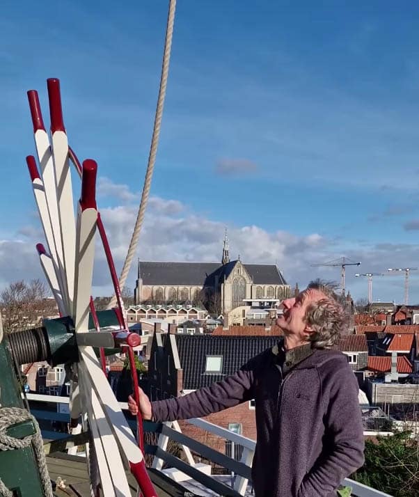 Cees Piet bij de molen met op achtergrond de Grote Kerk