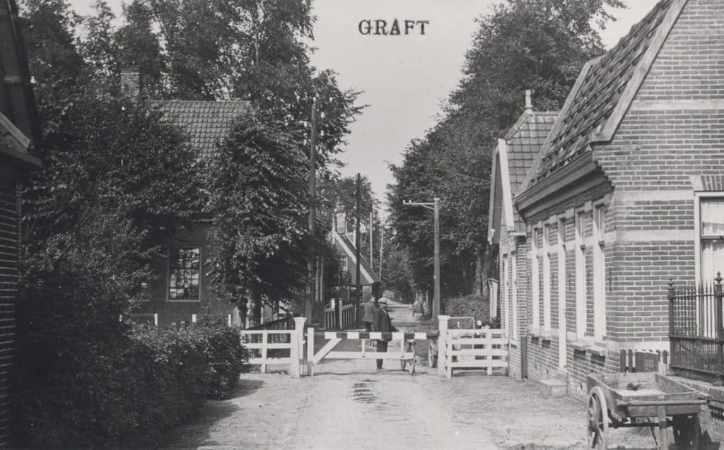 Prentbriefkaart van Raadhuis Graft. Grafter tol in de Raadhuisstraat. De tol werd tot 1929 gepacht door de gezusters Sanders. Pas in 1942 zou de tol definitief verdwijnen. Het huis rechts is van veldwachter Hendriksen. Foto P Jonker Circa 1928 Collectie Kaptein.